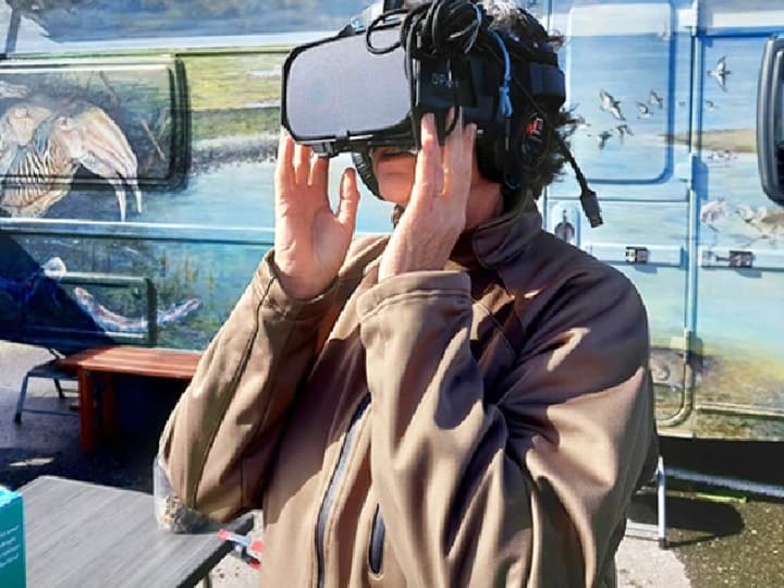 Een bezoeker met een VR-bril bij de Deltawagen van Natuurmonumenten