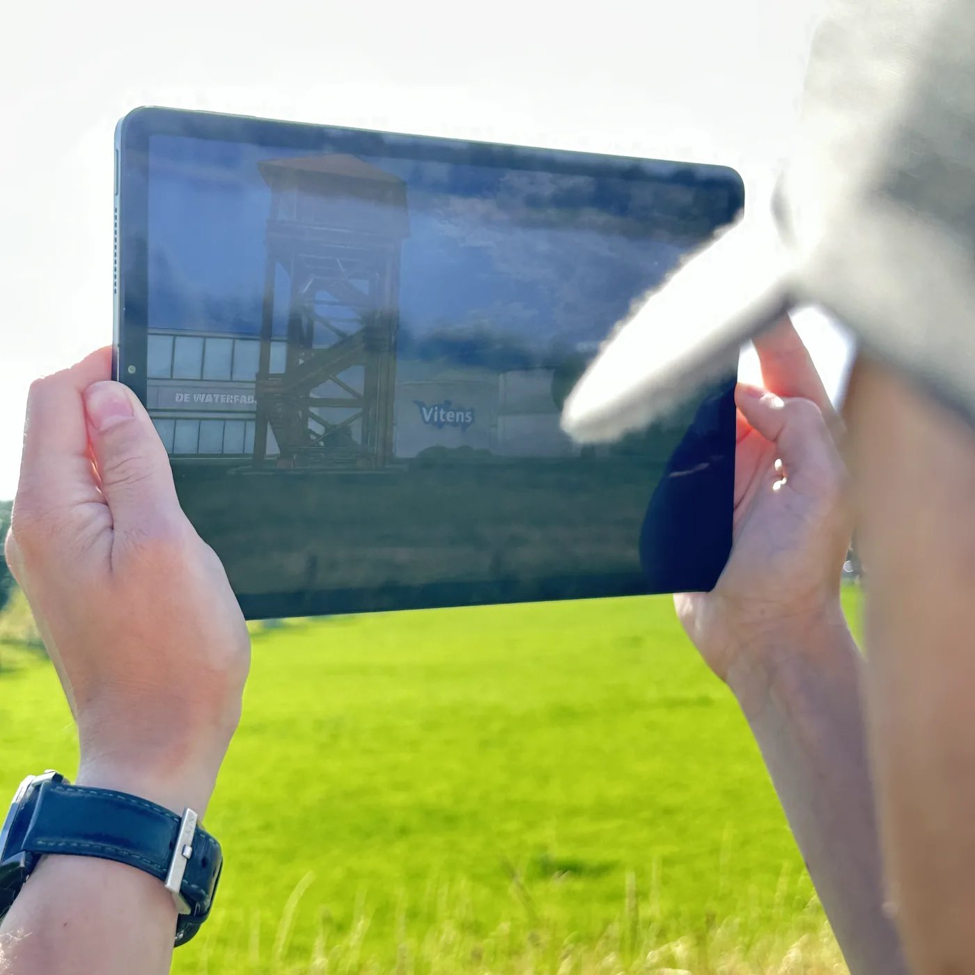Iemand houdt een tablet omhoog met het AR-model van de drinkwaterfabriek in beeld