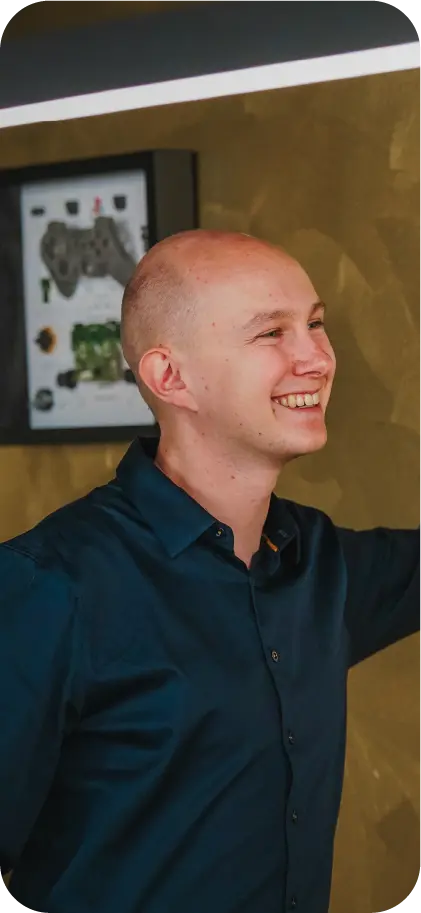 Lachende medewerker van VR-Innovations bij een ingelijste gamecontroller-poster op kantoor