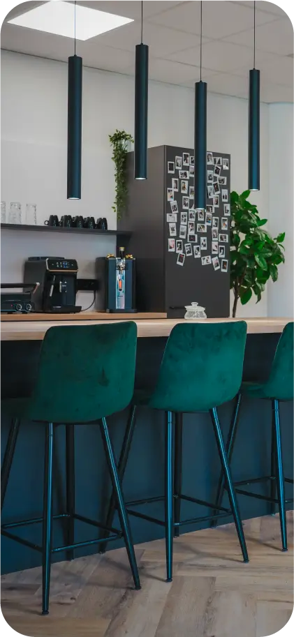Kantoorbar van VR-Innovations met groene velvet barkrukken, koffiemachine en een wand met polaroidfoto's