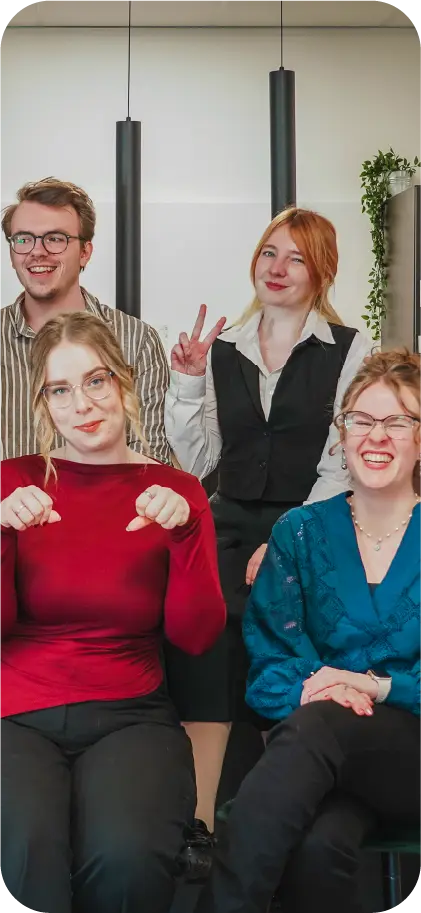 Vier collega's van het team van VR-Innovations poseren vrolijk samen op kantoor